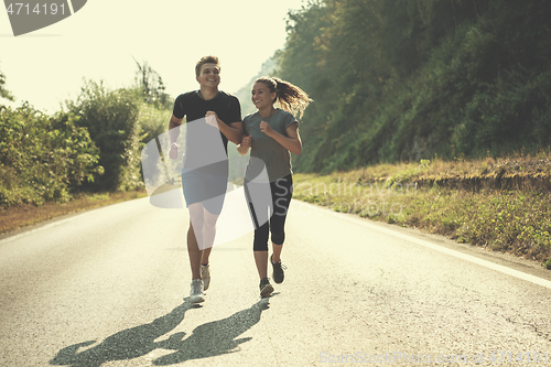 Image of young couple jogging along a country road