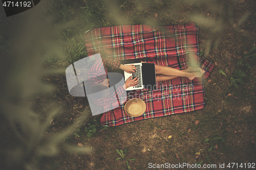 Image of top view of man using a laptop computer under the tree