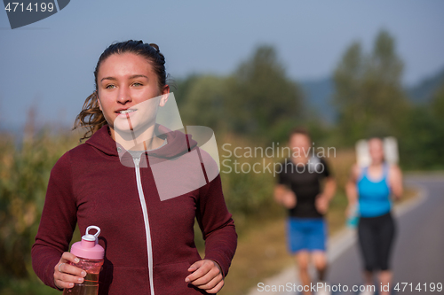 Image of young people jogging on country road