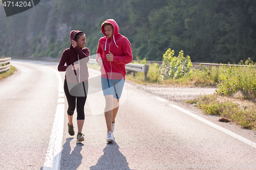 Image of young couple jogging along a country road