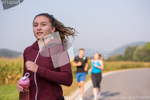 Image of young people jogging on country road