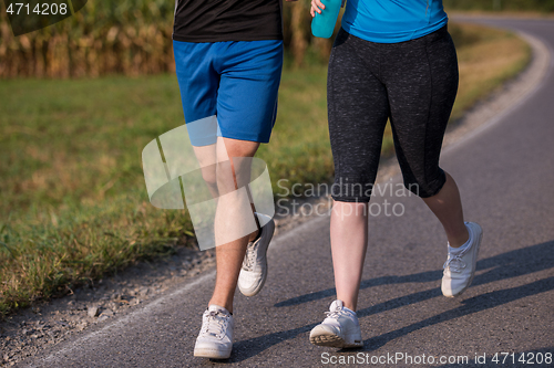Image of young couple jogging along a country road