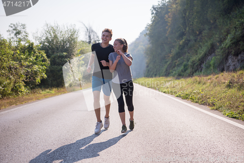 Image of young couple jogging along a country road