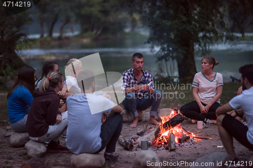 Image of young friends relaxing around campfire