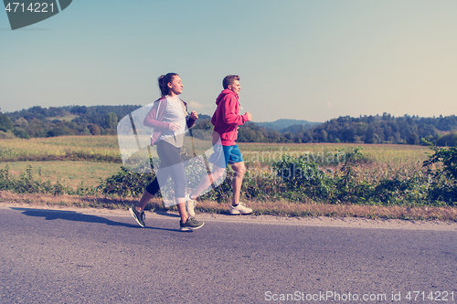 Image of young couple jogging along a country road