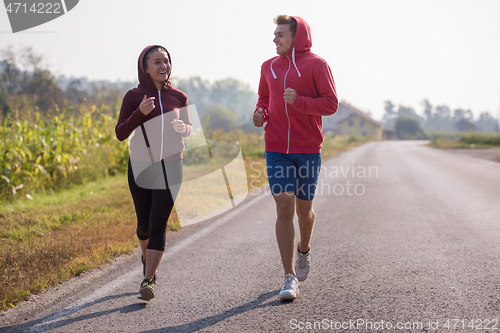 Image of young couple jogging along a country road