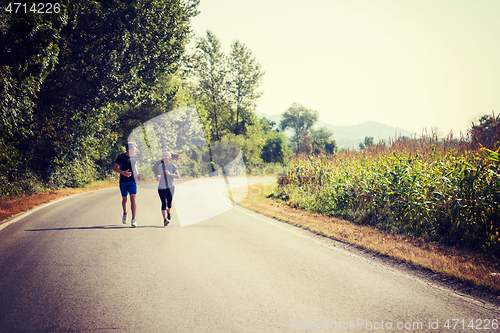 Image of young couple jogging along a country road