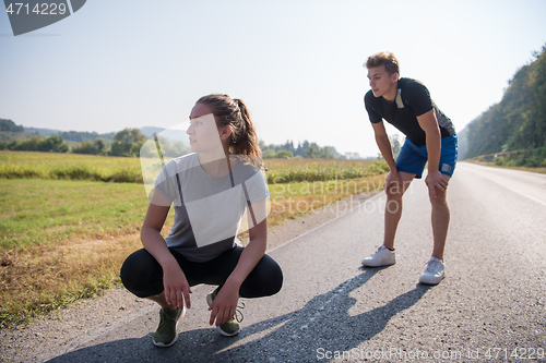 Image of young couple warming up and stretching on a country road