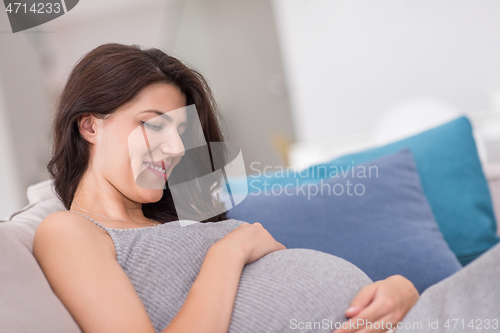 Image of pregnant woman sitting on sofa at home