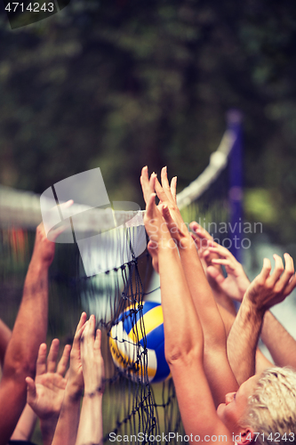 Image of group of young friends playing Beach volleyball