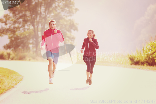 Image of young couple jogging along a country road