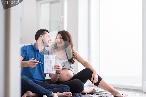 Image of pregnant couple checking a list of things for their unborn baby