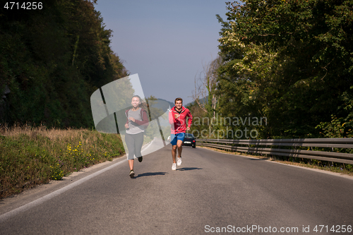 Image of young couple jogging along a country road