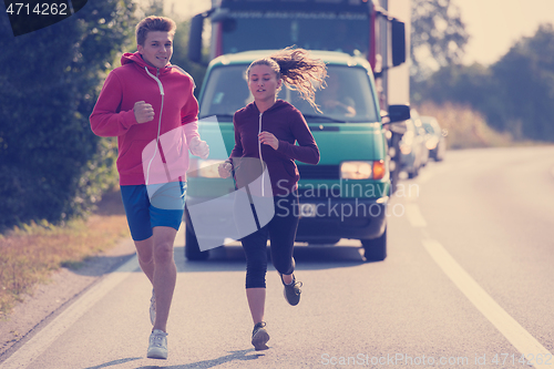 Image of young couple jogging along a country road