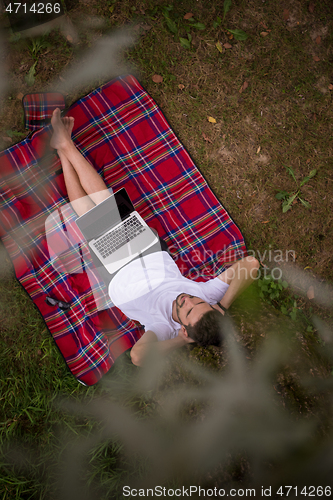 Image of top view of man using a laptop computer under the tree