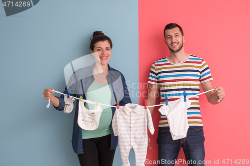 Image of young couple holding baby bodysuits