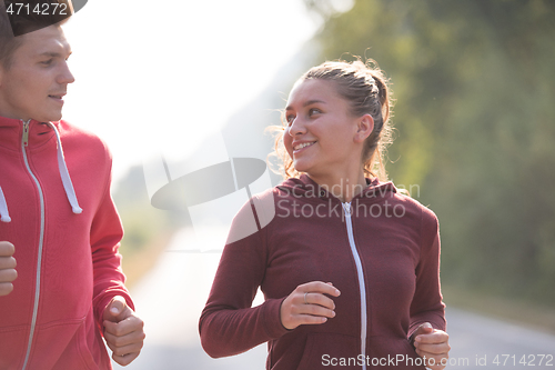 Image of young couple jogging along a country road