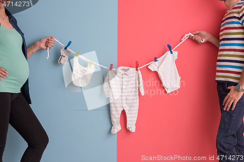 Image of young couple holding baby bodysuits