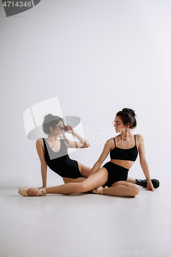 Image of Two young female ballet dancers against white studio background