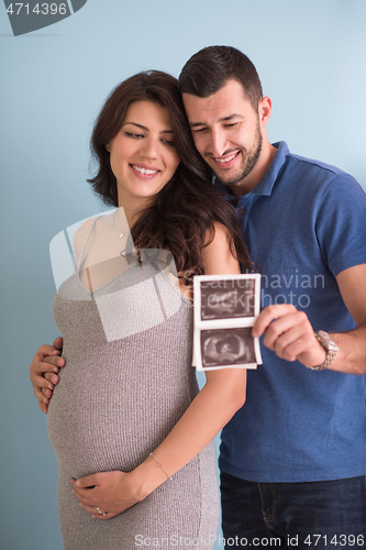 Image of couple looking ultrasound picture isolated on blue background