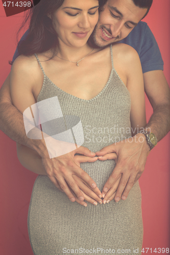 Image of pregnant  couple showing heart with their hands