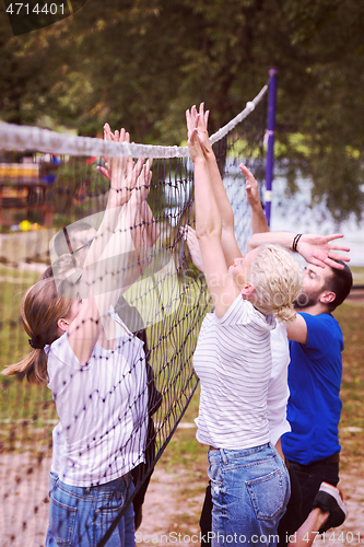 Image of group of young friends playing Beach volleyball