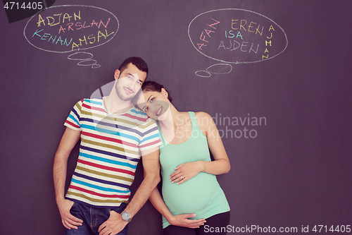 Image of pregnant couple writing on a black chalkboard