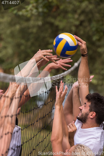 Image of group of young friends playing Beach volleyball