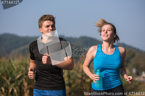 Image of young couple jogging along a country road