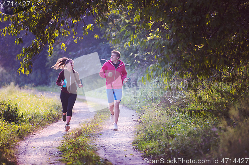 Image of young couple jogging along a country road