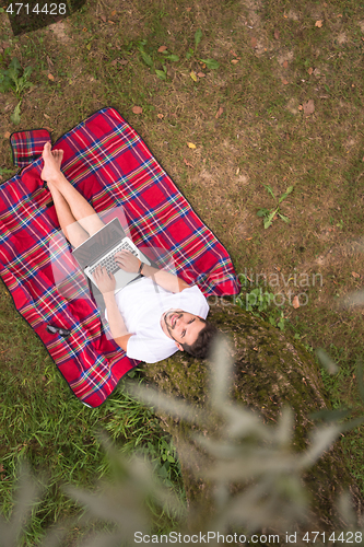 Image of top view of man using a laptop computer under the tree