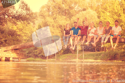 Image of friends enjoying watermelon while sitting on the wooden bridge