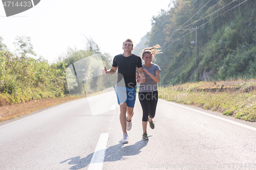 Image of young couple jogging along a country road