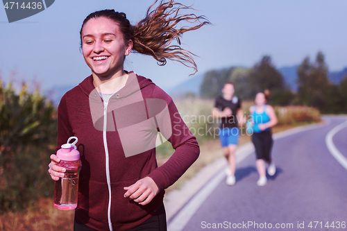 Image of young people jogging on country road