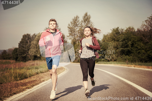 Image of young couple jogging along a country road