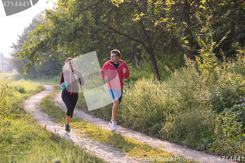 Image of young couple jogging along a country road