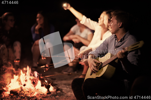 Image of young friends relaxing around campfire