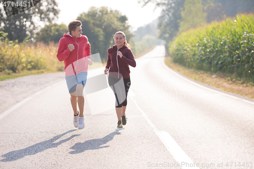 Image of young couple jogging along a country road
