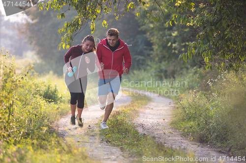 Image of young couple jogging along a country road