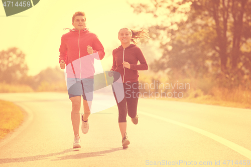 Image of young couple jogging along a country road