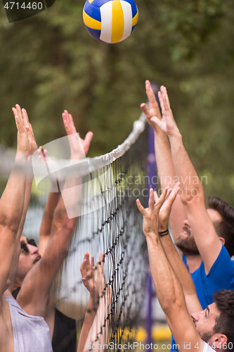 Image of group of young friends playing Beach volleyball