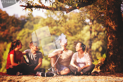 Image of friends smoking hookah on the river bank