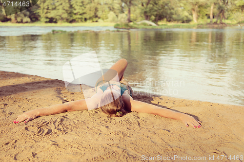 Image of girl in a green bikini relaxing on the riverbank