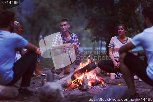 Image of young friends relaxing around campfire