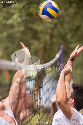 Image of group of young friends playing Beach volleyball