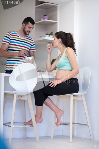 Image of couple eating fruit strawberries at kitchen