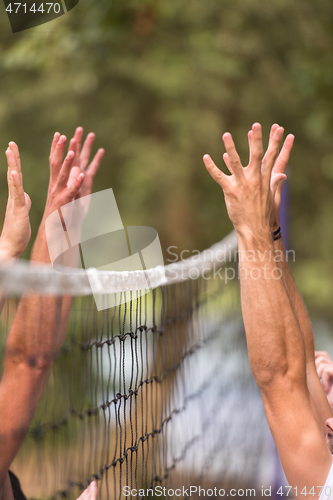 Image of group of young friends playing Beach volleyball