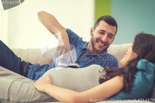 Image of young pregnant couple relaxing on sofa