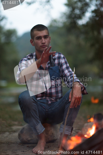 Image of young friends relaxing around campfire