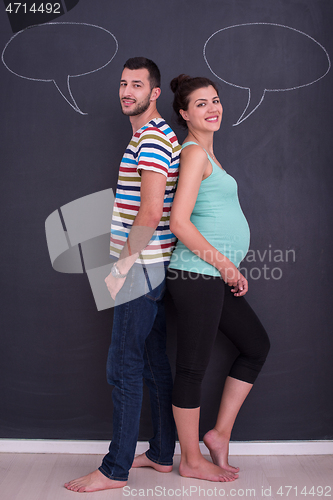 Image of pregnant couple writing on a black chalkboard